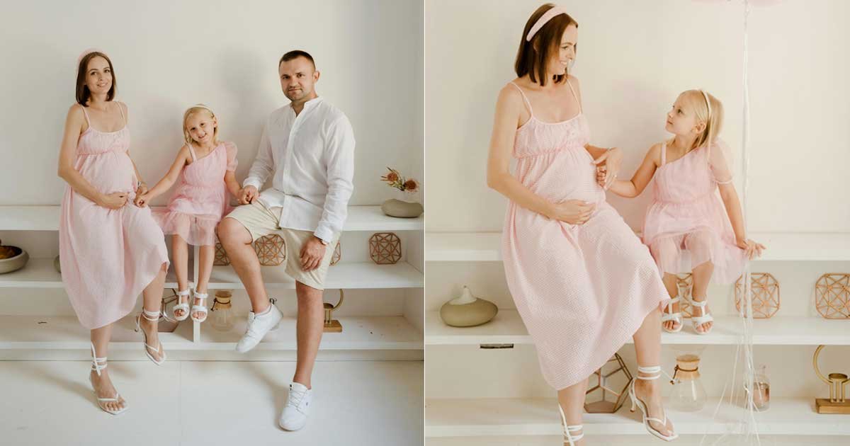Pregnant mother posing with her partner and young child indoors, showing a family maternity photoshoot with sibling bonding