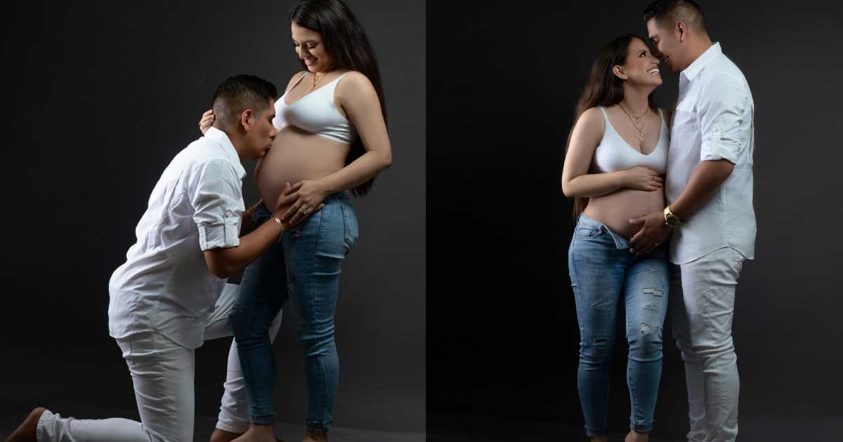 Expecting couple standing close, holding the baby bump and touching foreheads during an intimate maternity photoshoot