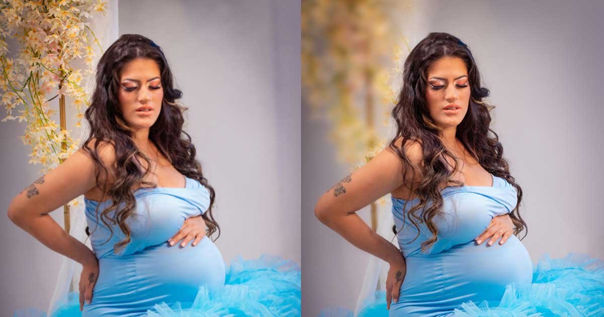 Pregnant woman in a blue gown posing indoors with a professionally enhanced and cleaned background for maternity photography